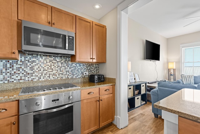 kitchen with backsplash, light wood finished floors, open floor plan, brown cabinetry, and stainless steel appliances