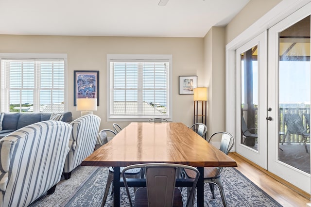 dining area with ceiling fan, wood finished floors, a healthy amount of sunlight, and french doors