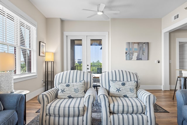 living area with french doors, a ceiling fan, wood finished floors, baseboards, and visible vents