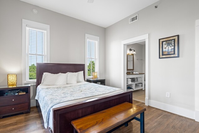 bedroom with ensuite bath, dark wood-type flooring, and ceiling fan