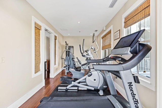 exercise area with wood finished floors, recessed lighting, baseboards, and visible vents