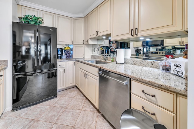 kitchen featuring black refrigerator, sink, stainless steel dishwasher, light stone countertops, and cream cabinetry