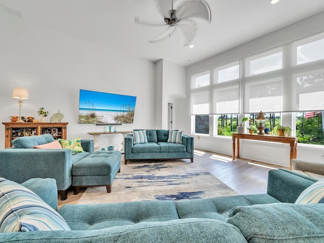 living room featuring ceiling fan, a towering ceiling, and wood-type flooring