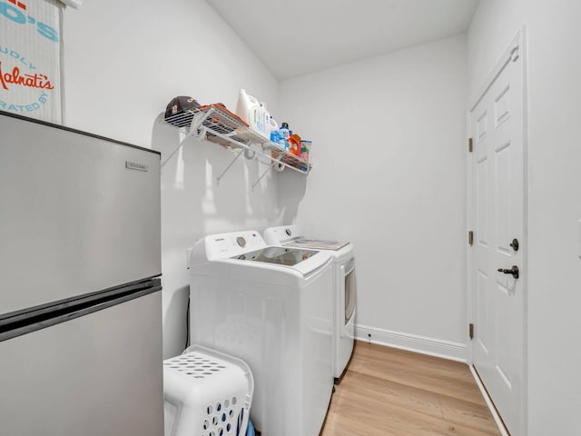 washroom with light hardwood / wood-style flooring and washing machine and dryer