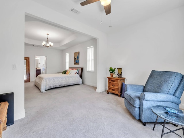 carpeted bedroom featuring a raised ceiling, connected bathroom, and ceiling fan with notable chandelier