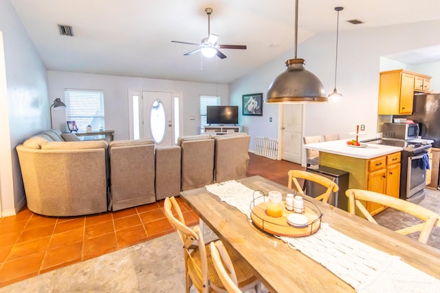 dining room with ceiling fan, light tile patterned floors, and vaulted ceiling