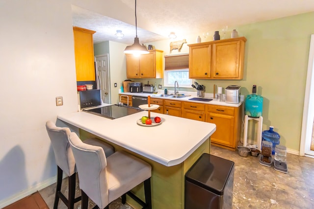 kitchen with a textured ceiling, kitchen peninsula, sink, and pendant lighting