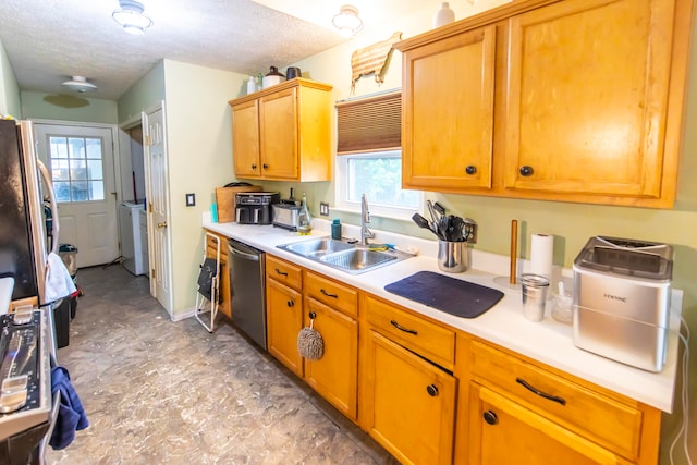 kitchen featuring appliances with stainless steel finishes, a textured ceiling, sink, and washer / clothes dryer