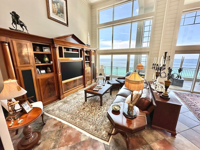 living room featuring crown molding, a healthy amount of sunlight, and a towering ceiling