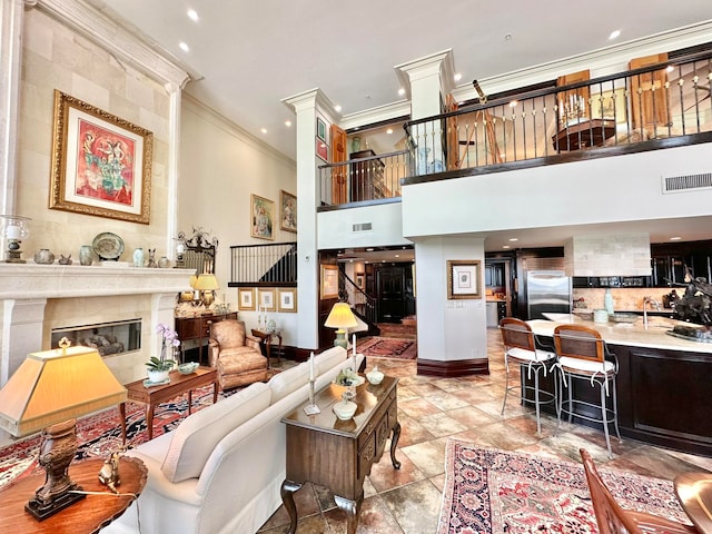 living room featuring a tiled fireplace, crown molding, and a high ceiling