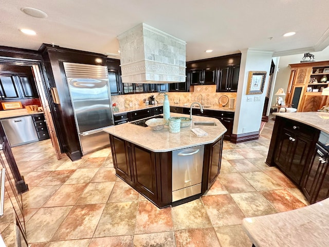 kitchen featuring tasteful backsplash, a center island with sink, ornamental molding, high quality fridge, and sink