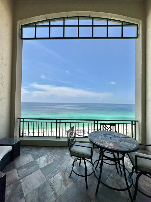 balcony with a water view and a view of the beach