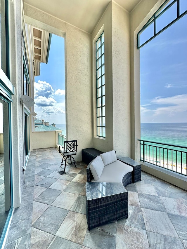 view of patio / terrace with a water view, a view of the beach, a balcony, and outdoor lounge area