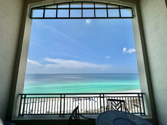 balcony with a water view and a view of the beach