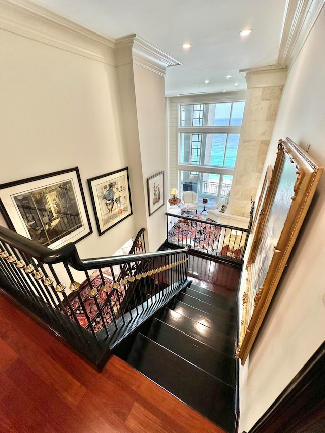 stairway featuring hardwood / wood-style floors, crown molding, and decorative columns