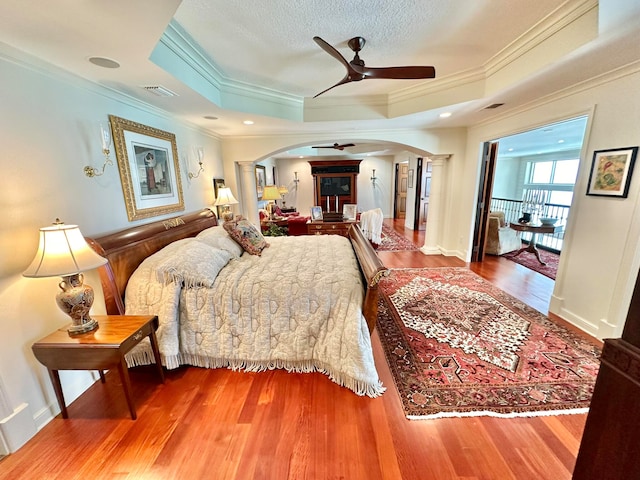 bedroom featuring crown molding, a tray ceiling, wood-type flooring, and ceiling fan