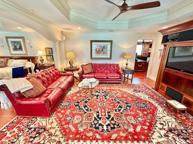 living room featuring ornate columns, crown molding, a tray ceiling, and ceiling fan