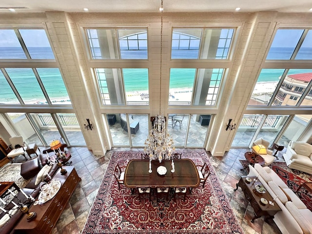 sunroom with a water view, a notable chandelier, and a beach view