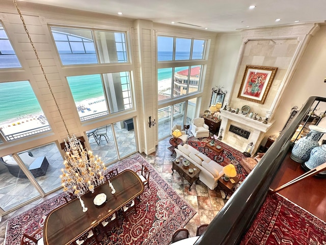 living room featuring a high ceiling, a water view, a view of the beach, and plenty of natural light