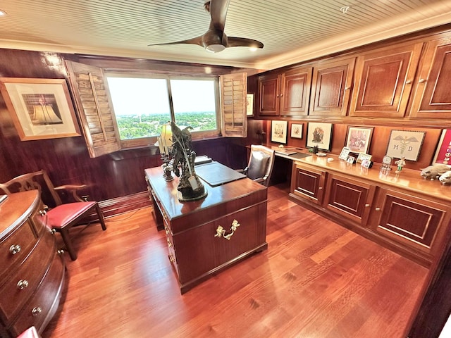 office space featuring built in desk, hardwood / wood-style floors, ceiling fan, and wood walls