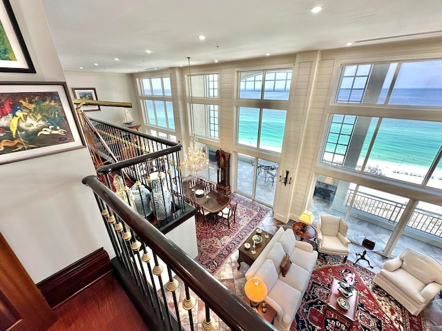 living room featuring an inviting chandelier, a healthy amount of sunlight, a water view, and a beach view