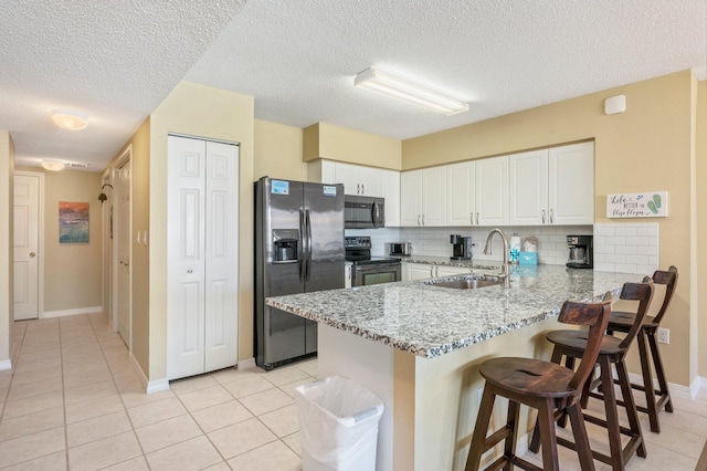 kitchen with appliances with stainless steel finishes, white cabinetry, backsplash, sink, and kitchen peninsula