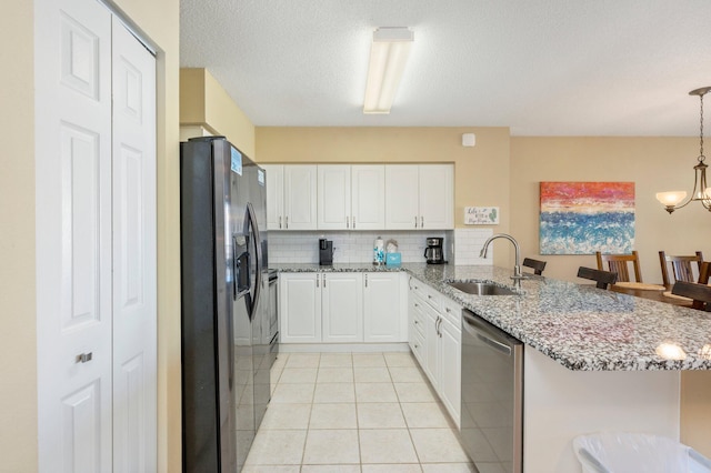 kitchen featuring light tile patterned flooring, stainless steel appliances, backsplash, sink, and kitchen peninsula