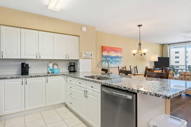 kitchen featuring sink, stainless steel dishwasher, kitchen peninsula, and light stone countertops