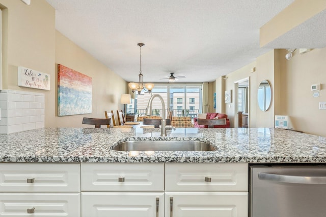 kitchen featuring sink, a textured ceiling, light stone counters, and stainless steel dishwasher