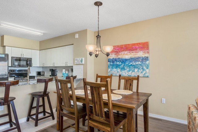 dining room with a textured ceiling, an inviting chandelier, and wood-type flooring