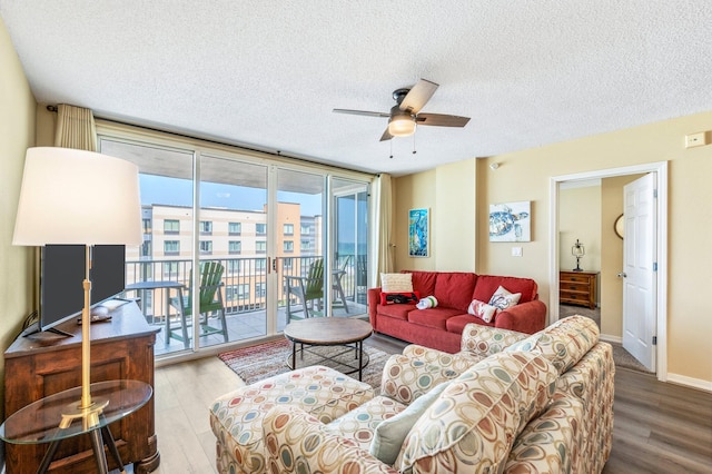 living room featuring a wall of windows, ceiling fan, a textured ceiling, and hardwood / wood-style floors