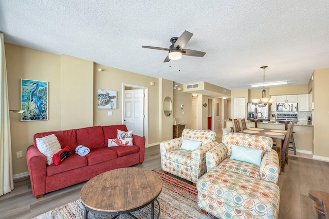 living room with hardwood / wood-style floors, sink, a textured ceiling, and ceiling fan with notable chandelier