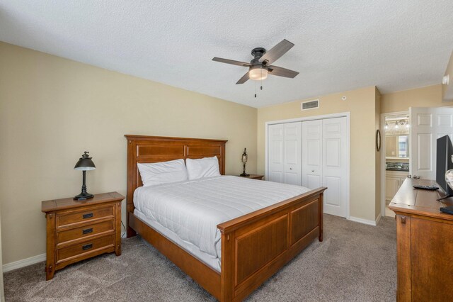 carpeted bedroom featuring a textured ceiling, a closet, and ceiling fan