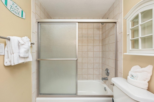 bathroom with shower / bath combination with glass door, a textured ceiling, and toilet