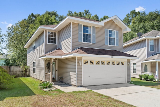 traditional home featuring a shingled roof, concrete driveway, an attached garage, fence, and a front lawn