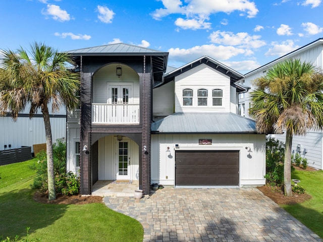 view of front of property featuring a front yard, a garage, and a balcony