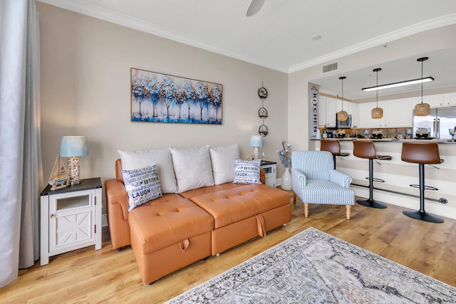 living room featuring ornamental molding, light hardwood / wood-style floors, and ceiling fan