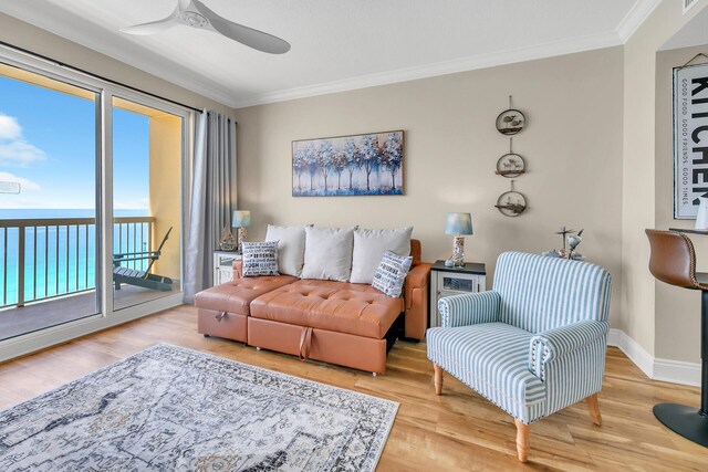 living room featuring ornamental molding, light hardwood / wood-style flooring, a water view, and ceiling fan