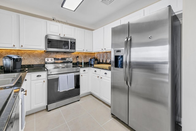 kitchen featuring white cabinetry, backsplash, light tile patterned flooring, and appliances with stainless steel finishes