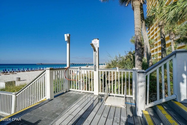 wooden deck featuring a water view and a view of the beach