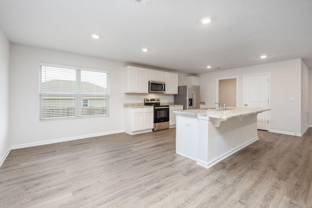 kitchen featuring light wood-type flooring, sink, stainless steel appliances, and a kitchen island with sink