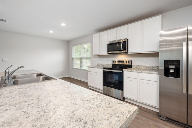 kitchen featuring sink, stainless steel appliances, hardwood / wood-style floors, and white cabinetry