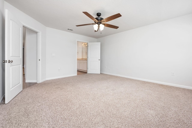 unfurnished bedroom with ceiling fan, ensuite bathroom, and light carpet