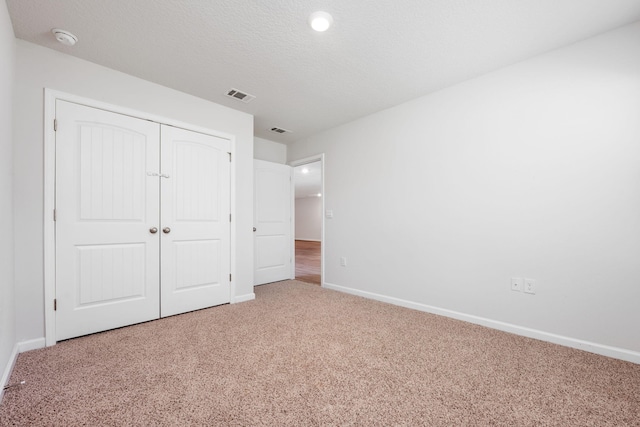 unfurnished bedroom featuring light carpet and a closet