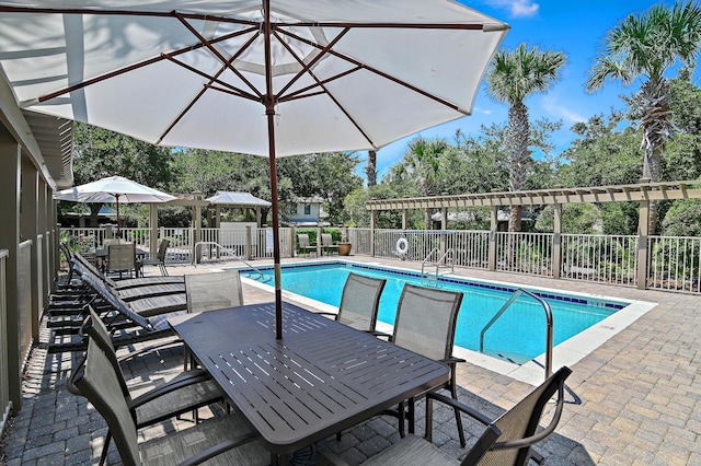 community pool featuring outdoor dining space, a patio area, and fence