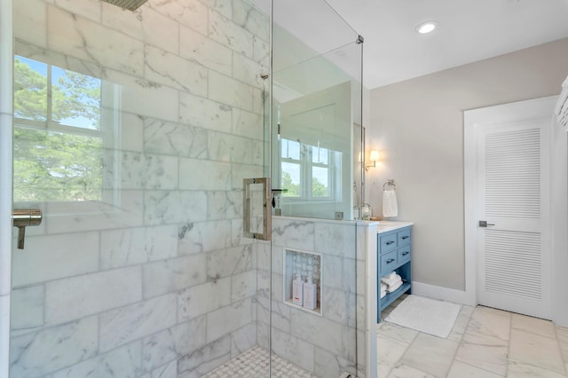 bathroom featuring marble finish floor, tiled shower, vanity, and a healthy amount of sunlight