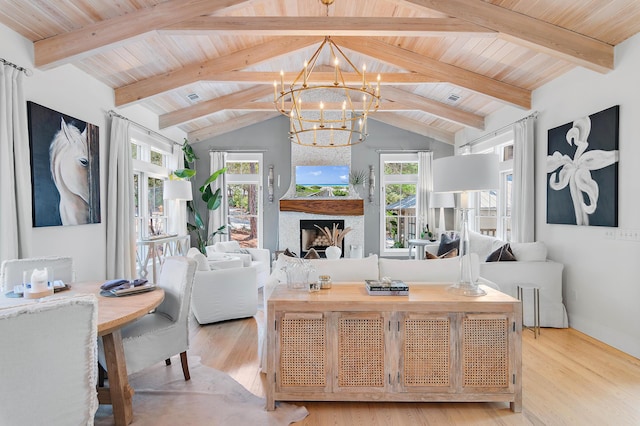 living room with a chandelier, lofted ceiling with beams, a fireplace, and a wealth of natural light