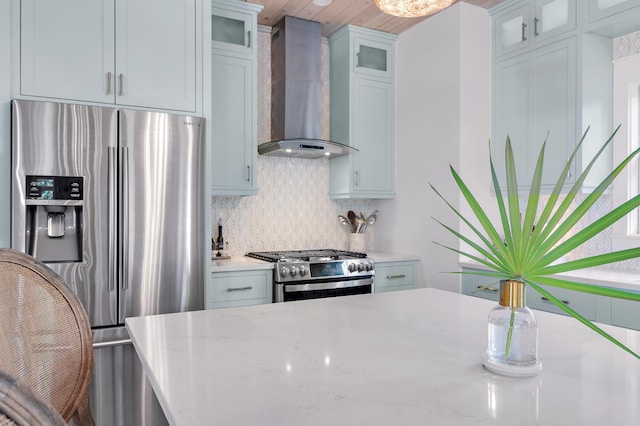 kitchen with stainless steel appliances, wall chimney range hood, light stone counters, and tasteful backsplash