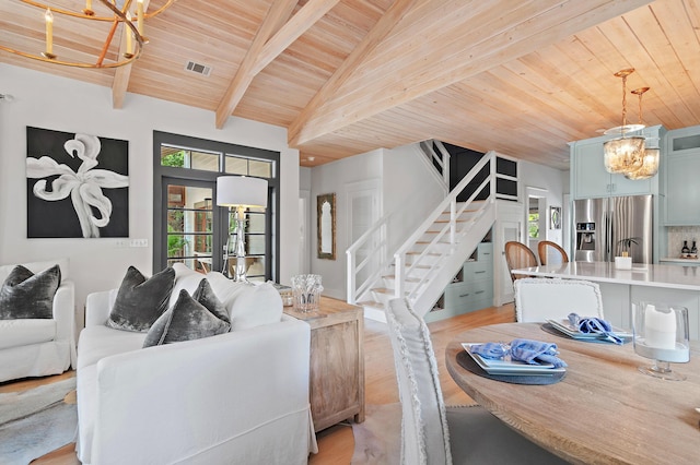 living room with visible vents, a notable chandelier, stairway, and light wood finished floors