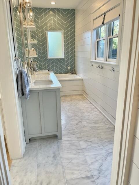 full bathroom with wood walls, a bath, and vanity